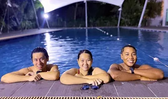 3 adults smiling happily in the pool