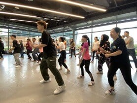 Students of all ages following dance moves in a dance class