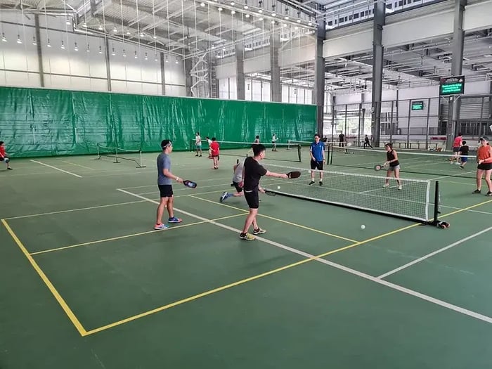 People playing pickleball in a large indoor pickleball court area