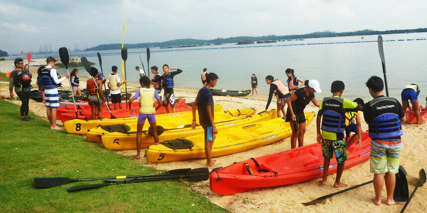 Rows of kayak boats lined up next to one another with people ready to board